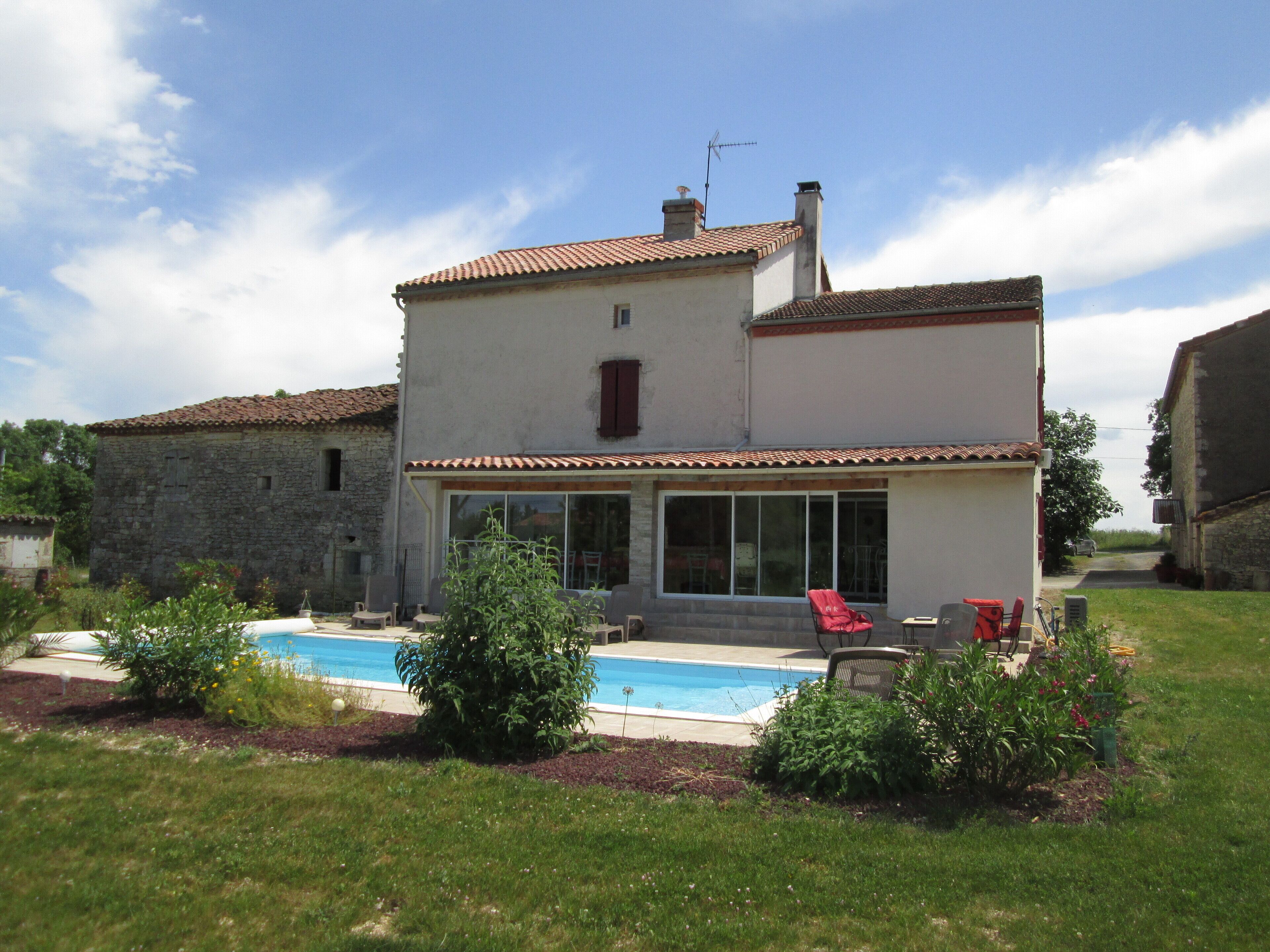 Une maison à deux étages avec une piscine, un jardin et une chaise rouge.