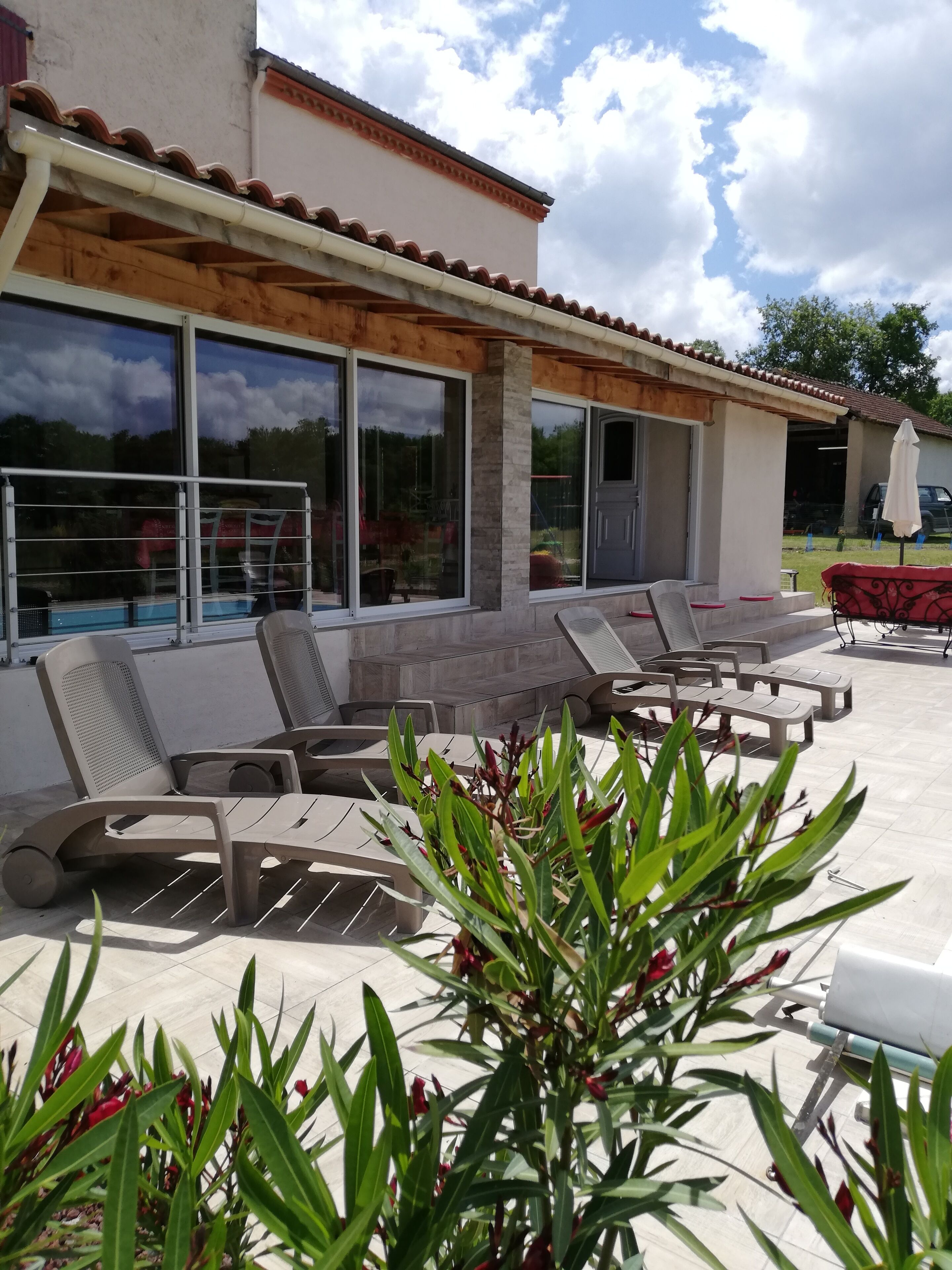 An outdoor patio area with sun loungers, a pool, and large windows.