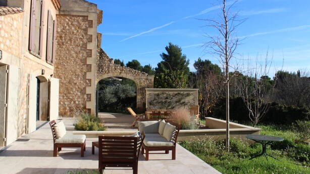 Une terrasse extérieure avec des murs en pierre, une arche en pierre et du mobilier d’extérieur.