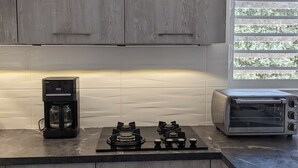 A modern kitchen with grey wooden cabinets, a coffee maker, a gas stove, and a toaster. - DIVE FROM YOUR DOORSTEP!  Oceanview Townhome with Diving Amenities at Marazul E1 (Sabana Westpunt)