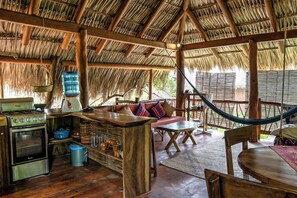 Un intérieur rustique avec un toit de chaume, des meubles en bois, un coin bar et un hamac.