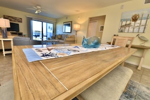 A dining table with a placemat, a blue glass bowl, and a bench. - Sundown B 14 (Pensacola)