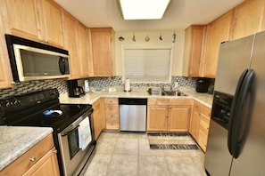 A kitchen with wooden cabinets, a stainless steel refrigerator, a dishwasher, a microwave, and a stove.