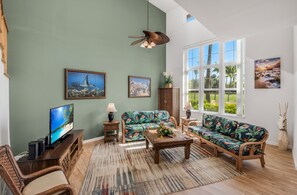 Una sala de estar con televisión, sofá, mesa de centro y objetos decorativos.