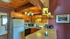 Una cocina con armarios de madera, un refrigerador, un microondas y una cafetera.