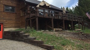 Une cabane rustique en rondins de bois, dotée d’une terrasse en bois et d’un porche abrité.