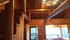 Un intérieur en bois avec un escalier, un lustre et une fenêtre offrant une vue.