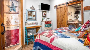 Une chambre à coucher de style rustique, avec un lit, une commode, un bureau et un téléviseur.