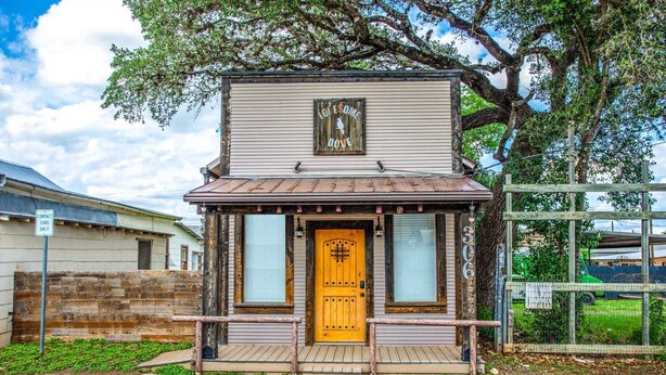 Un petit bâtiment en bois avec une porte jaune, une enseigne au-dessus de la porte et le numéro « 306 » sur le côté droit.