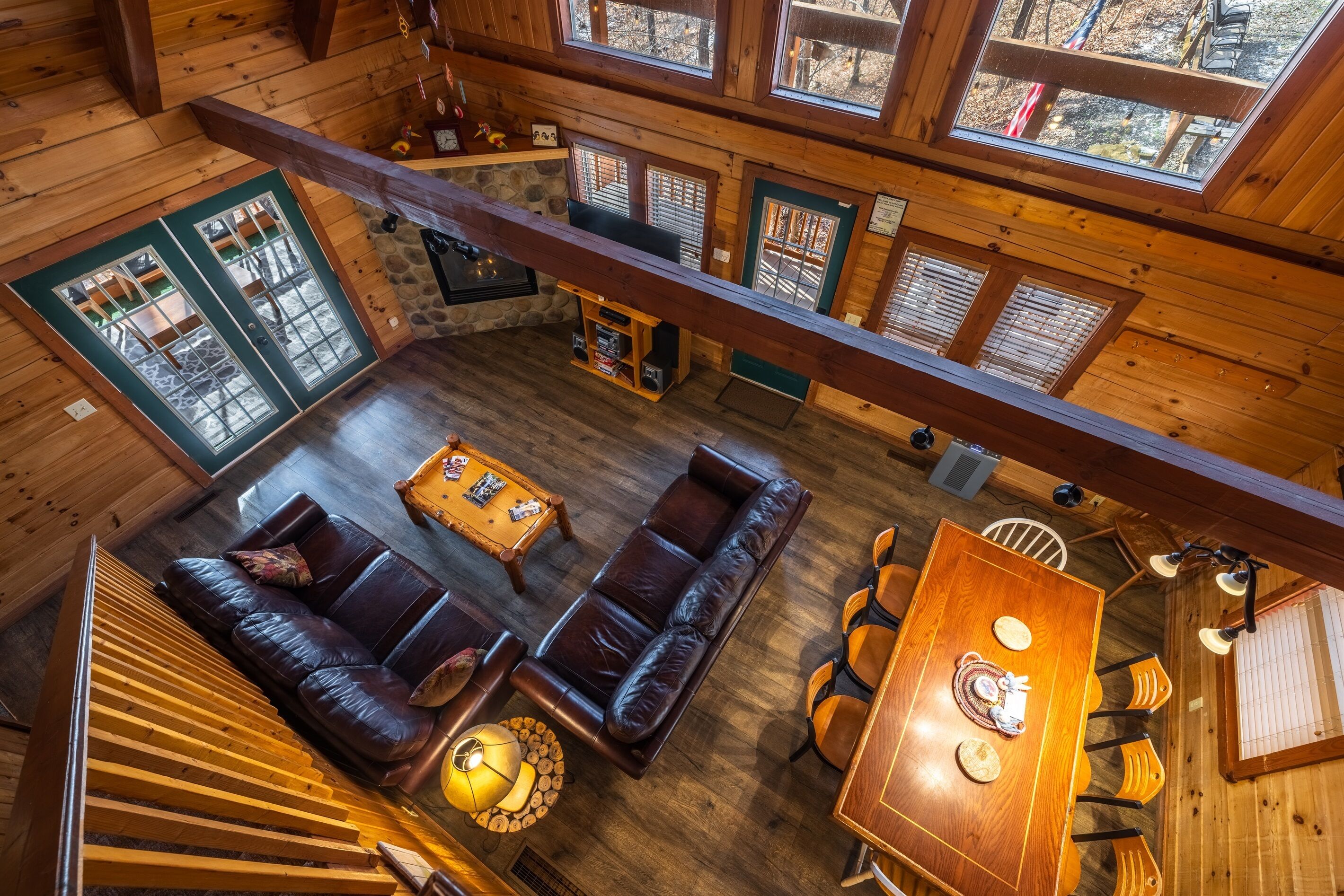 A wooden cabin interior with a living area, dining table, and a fireplace.