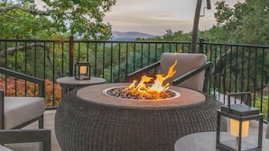 An outdoor patio with a round fire pit, seating, and an umbrella. - Resort-like Villa, 50' Infinity Edge Pool, Garden, Peaceful, Luxurious (Sonoma)