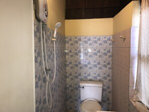 Un baño pequeño con inodoro, ducha y un grifo empotrado.