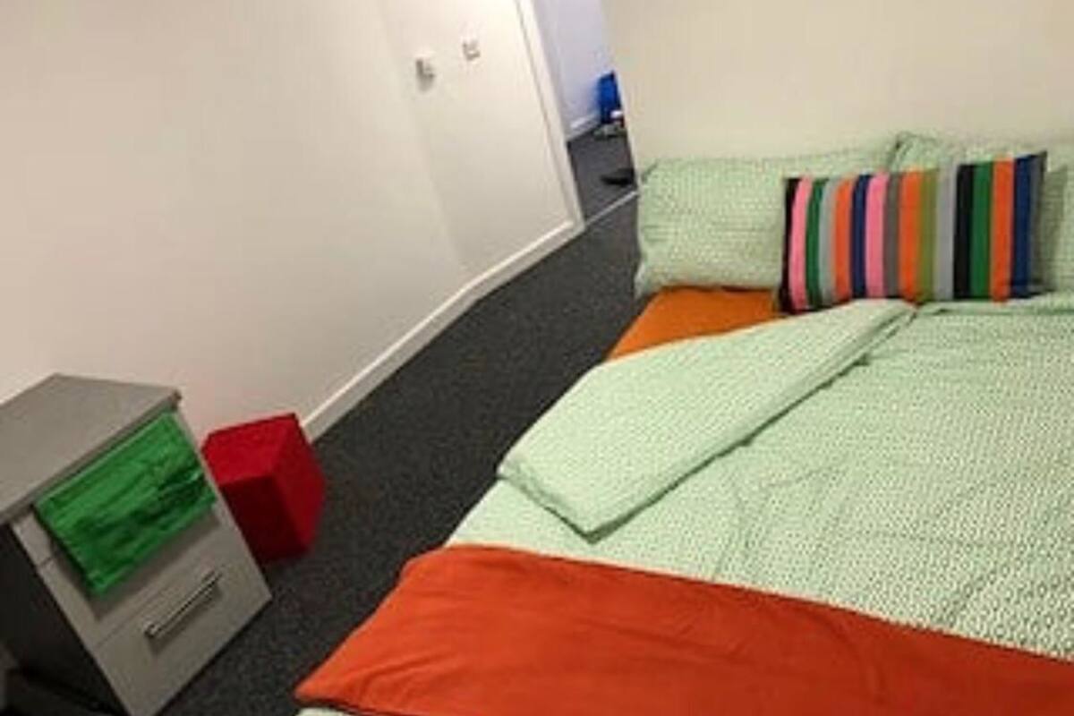 A room with a bed, a desk, and a filing cabinet.