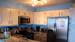 A kitchen with granite countertops, stainless steel appliances, and white cabinetry.