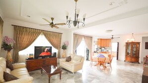 Uma sala de estar ampla com televisão, sofá, mesa de centro e área de jantar com cadeiras e mesa.