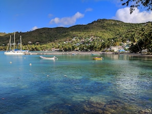 A coastal scene with clear water, boats, and a hillside with buildings. - Sunset Lane (Laborie)