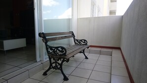 A wooden bench with ornate metal legs in a corner of a room with tiled flooring and a white wall. - Beautiful luxury apartment near (Zone 16)