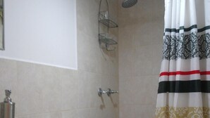 A bathroom with a toilet, sink, shower, and a patterned shower curtain. - Beautiful luxury apartment near (Zone 16)
