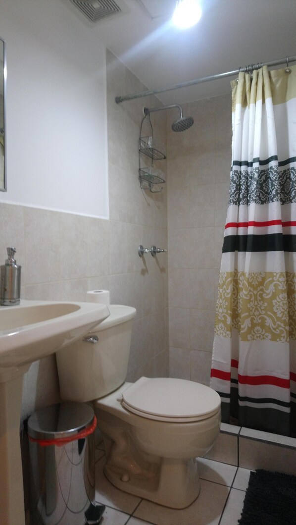 A bathroom with a toilet, sink, shower, and a patterned shower curtain. - Beautiful luxury apartment near (Zone 16)