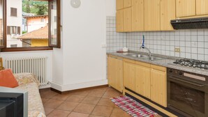 Ett kompakt kök med träskåp, en gasspis och ett fönster med utsikt över ett bostadsområde.