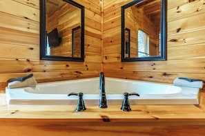 Ein Badezimmer einer Holzhütte mit einer Badewanne, zwei Spiegeln und einem Handtuch an der Seite.