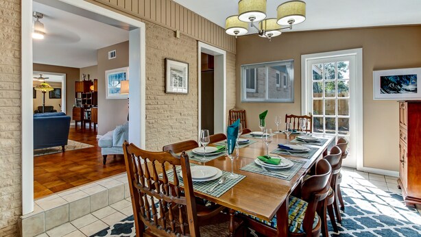 A dining area with a wooden table set for six, surrounded by chairs, with a chandelier above. - Heated Private Pool - Bring your Kayak  (Savannah)