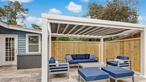 An outdoor patio area with a covered seating arrangement, a wooden fence, and a house in the background. - Heated Private Pool - Bring your Kayak  (Savannah)