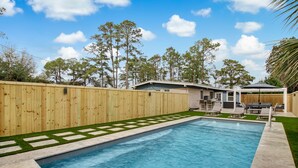A rectangular swimming pool with a wooden fence and a small house in the background. - Heated Private Pool - Bring your Kayak  (Savannah)