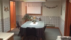 A compact kitchen with a dining table, chairs, a stove, and a window with a curtain. - 3 Bedroom, Cozy Cottage Near Seney Wildlife Refuge (Seney)