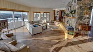 A spacious living room with a large sofa, coffee table, and a stone fireplace. - Nunda Ranch near Letchworth State Park (Nunda)