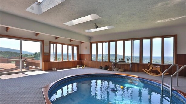 A large indoor swimming pool with a view of mountains through large windows. - Nunda Ranch near Letchworth State Park (Nunda)