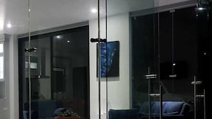 A modern living room with a glass partition, a blue sofa, and a coffee table. - House of Views (La Fortuna)