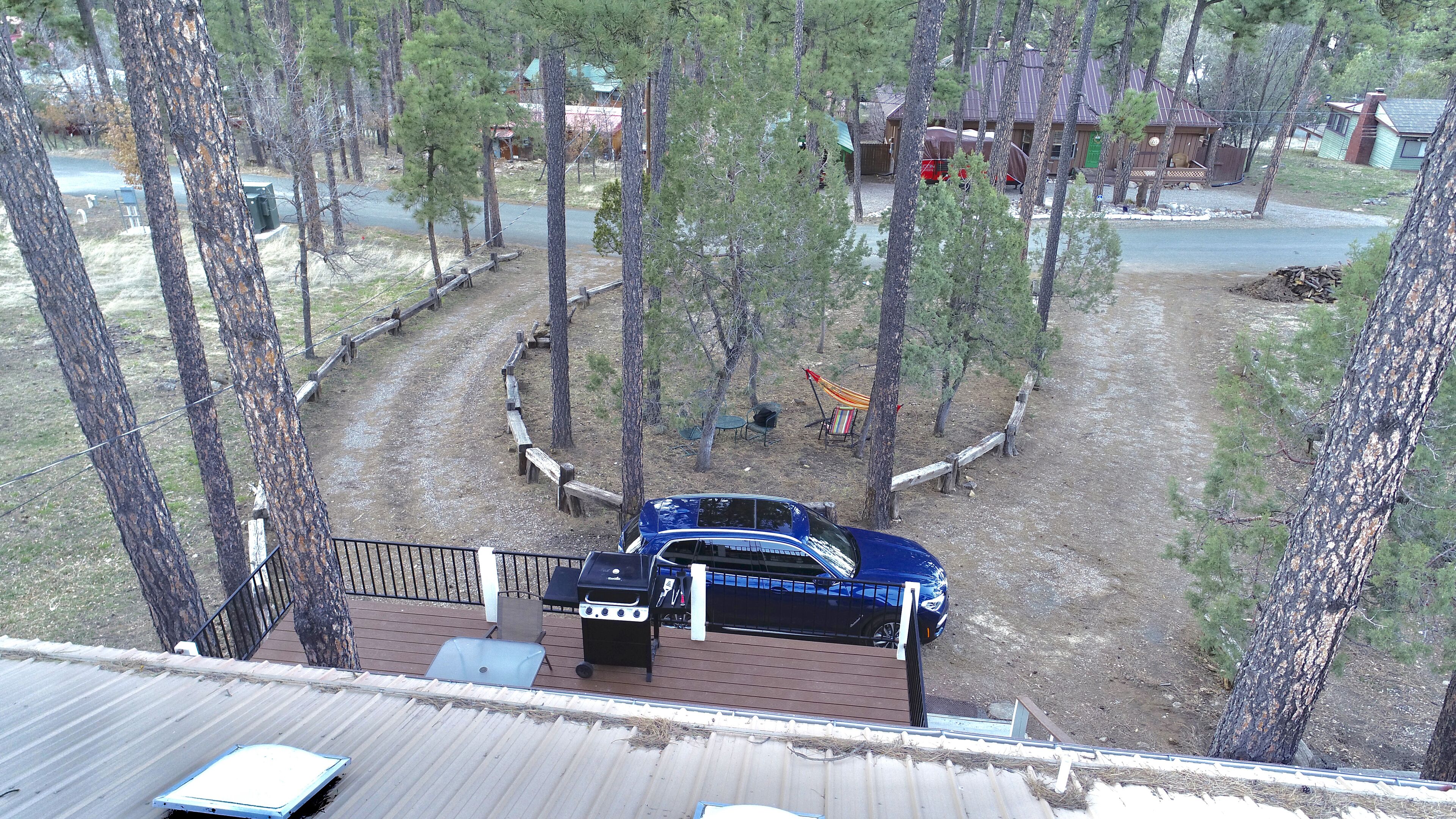 Une vue d’une cabane entourée d’arbres, avec une terrasse et un espace salon extérieur.