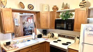 A kitchen with wooden cabinets, a stove, a microwave, and a refrigerator. - Cozy, Rustic Pine Ridge Cabin with beautiful views - Midtown Ruidoso (Ruidoso)