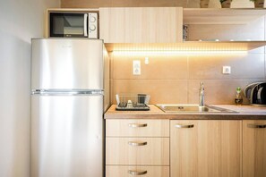 Una cocina con un refrigerador de acero inoxidable, un microondas, un lavamanos y gabinetes de madera.