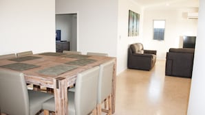 Un coin repas avec une table et des chaises en bois, un canapé et un téléviseur dans le salon.