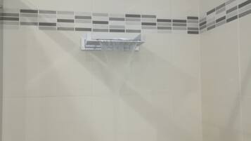 A bathroom with a shower area, a towel rack, and a tiled wall with a decorative border.