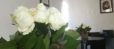 Ein Essbereich mit Tisch und Stühlen, einer Vase mit weißen Rosen und einer Decke mit Fresken.