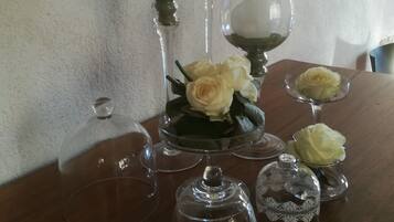A table with several wine glasses and a glass vase with white roses.