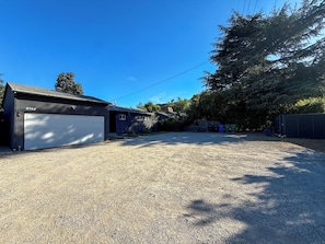 A residential area with a garage, a house, and a gravel driveway.
