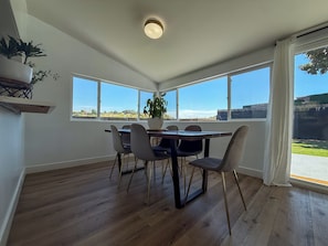 Uma sala de jantar com uma mesa de madeira, seis cadeiras e um vaso com planta.