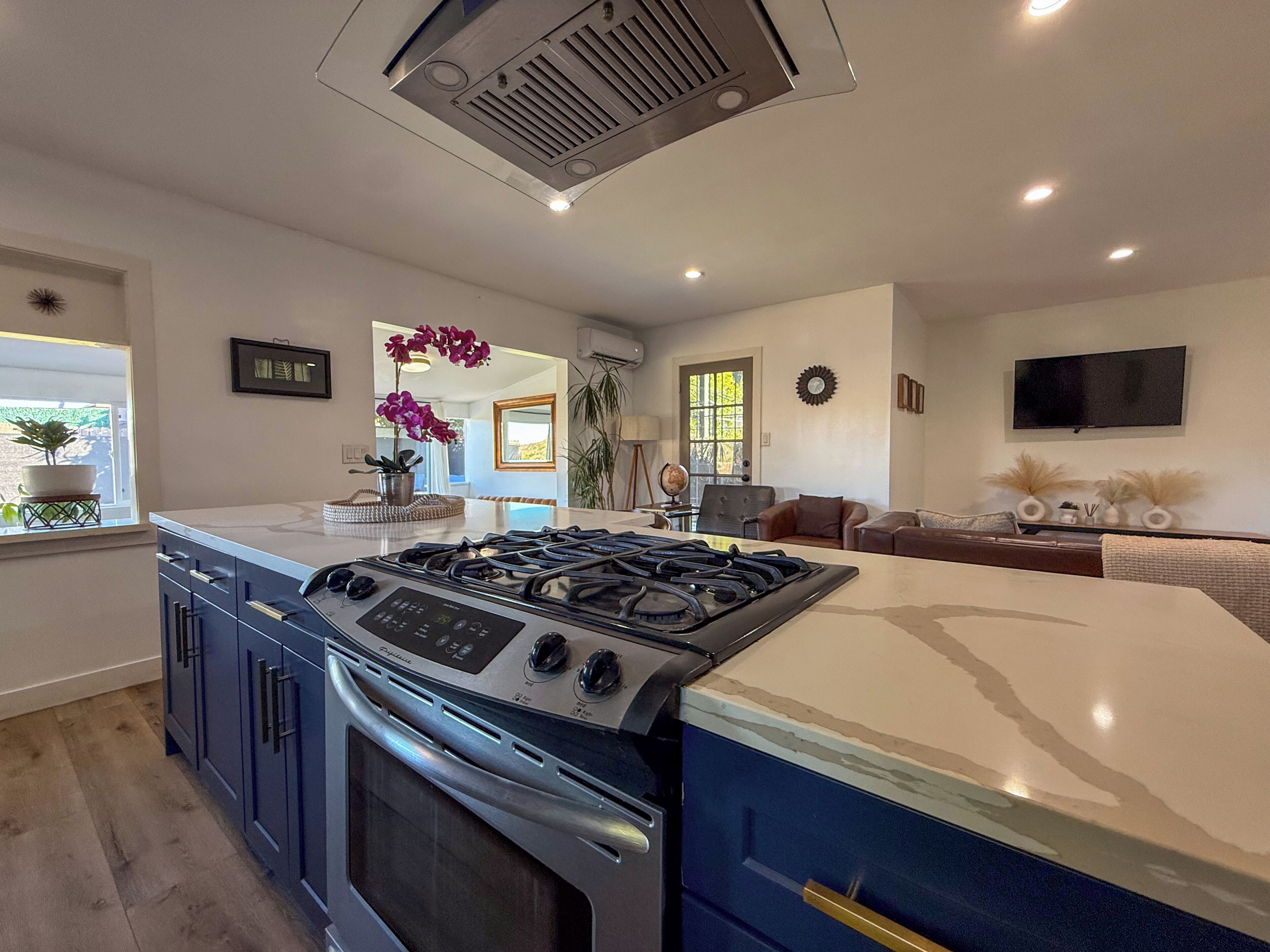 A modern kitchen with a central island, built-in oven, and a gas stove.