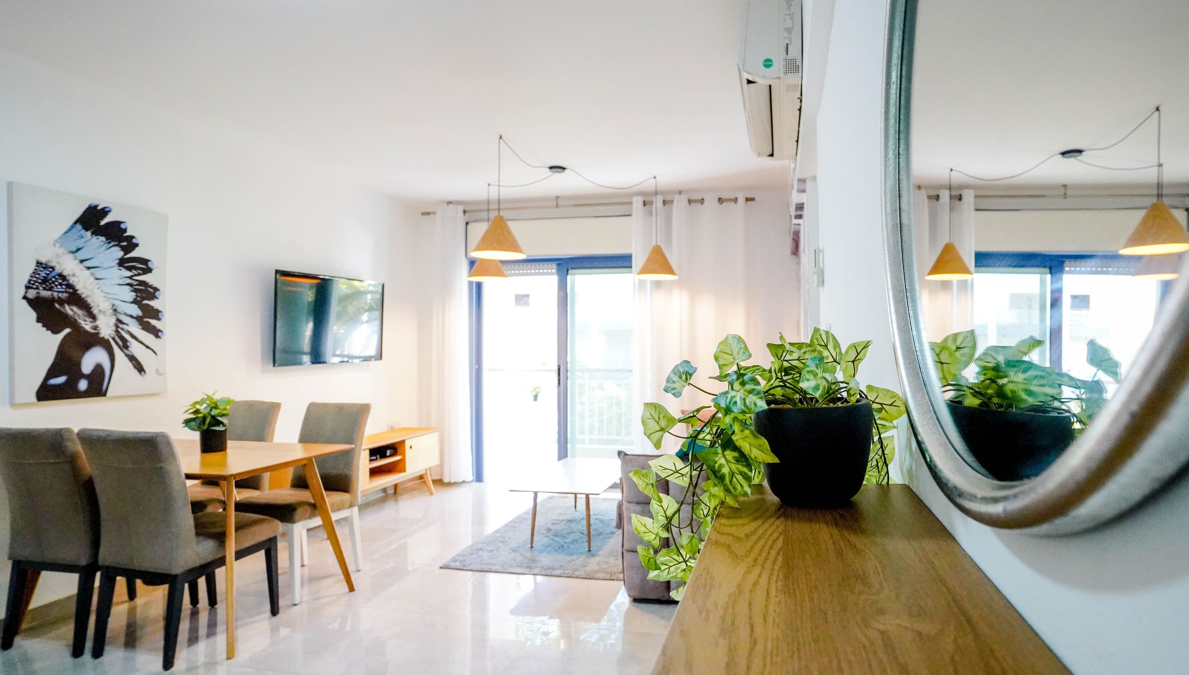 Una sala moderna con comedor, ventanas amplias y un televisor de pantalla plana.