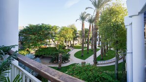 A courtyard with palm trees, a curved pathway, and a white building with balconies.