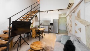 A modern apartment with a staircase, a dining area, a kitchen, and a living room.