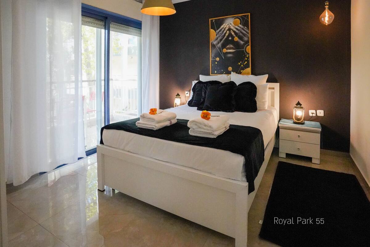 A modern bedroom with a large bed, white bedding, a black throw, and two bedside lamps.