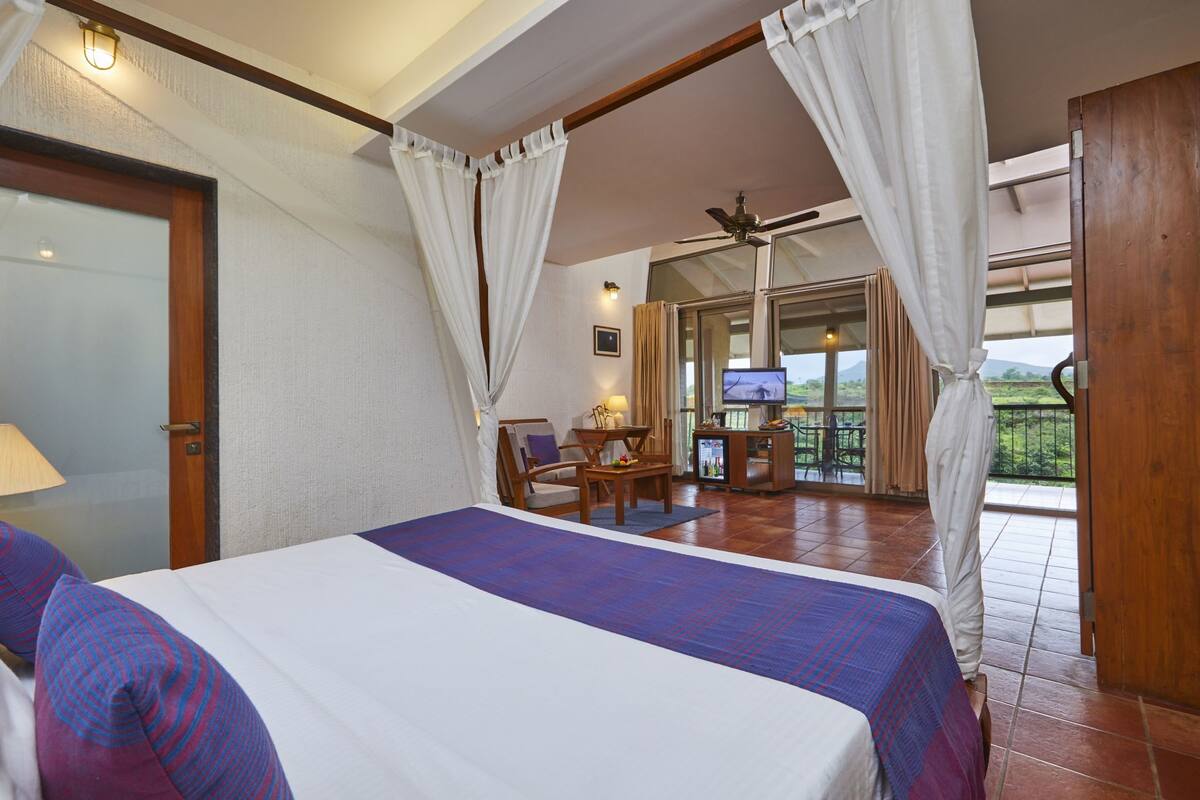 A hotel room with a bed, a desk, a chair, and a TV.