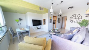 Una sala de estar moderna con un sofá, sillas, un televisor y un comedor con mesa y sillas.