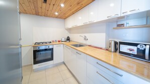 Una cocina moderna con armarios blancos, encimera de madera, horno empotrado y cafetera.