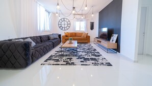 Una sala de estar moderna con un sofá oscuro, un sofá de tonos claros, una mesa de centro y un tapete blanco y negro.
